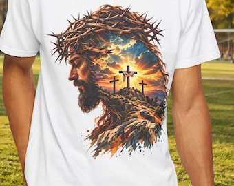 May include: A white t-shirt featuring a graphic print of a side profile of a bearded figure wearing a crown of thorns, with a landscape scene of three crosses on a hill against a sunset sky integrated into the silhouette of the head.
