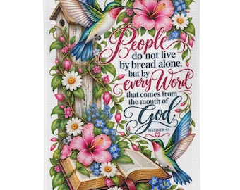 May include: A white kitchen towel featuring a colorful illustration of two hummingbirds, a wooden birdhouse, an open book, and pink hibiscus flowers. The text reads: People do not live by bread alone, but by every Word that comes from the mouth of God.
