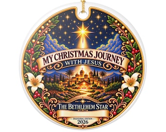 May include: A round ceramic ornament featuring a vibrant illustration of a nativity scene under a bright star. Text reads: MY CHRISTMAS JOURNEY WITH JESUS, THE BETHLEHEM STAR, and INAUGURAL EDITION 2026. The design includes holly, berries, and lilies.