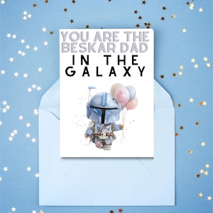 Może przedstawiać: Kartka okolicznościowa z napisem "YOU ARE THE BESKAR DAD IN THE GALAXY" i ilustracją postaci trzymającej balony. Karta znajduje się w jasnoniebieskiej kopercie, na niebieskim tle z konfetti w kształcie gwiazd.