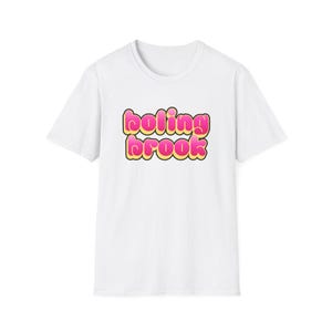 Pode incluir: Camiseta branca com o texto "boling brook" em fonte de bolhas. O texto é rosa e amarelo, com contorno preto. A camiseta tem mangas curtas e gola redonda.