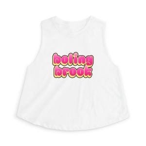 Pode incluir: Top curto branco sem mangas com o texto "boling brook" em letras de bolha rosa e amarelo com contorno preto. O top tem decote redondo e cavas.