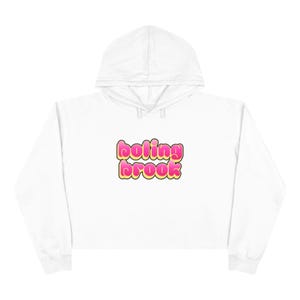Pode incluir: Moletom branco curto com a inscrição "boling brook" em letras de bolhas rosa e amarelo. O moletom com capuz tem capuz com cordão e mangas compridas. Uma parte de cima casual e confortável.