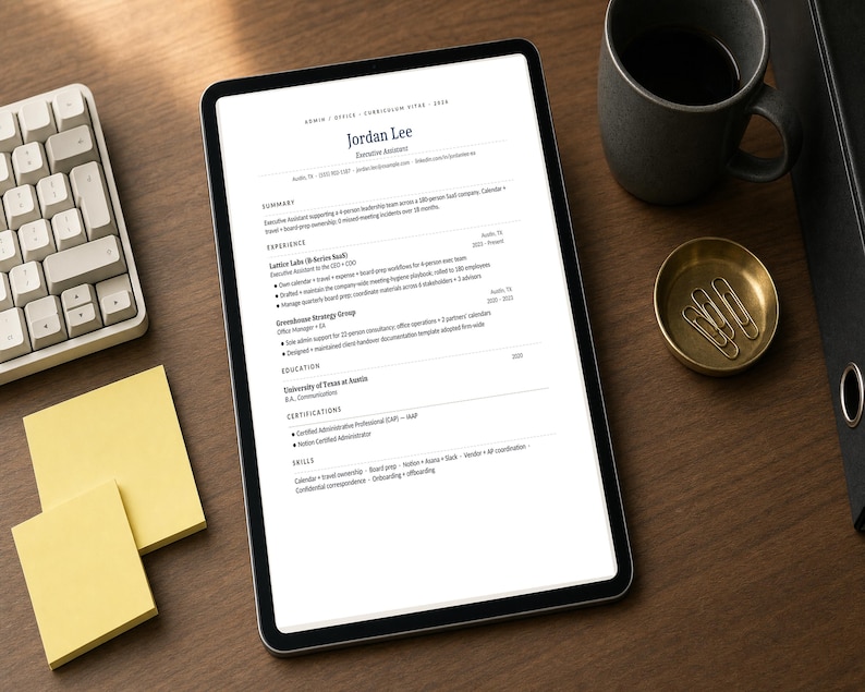 May include: A digital tablet displaying a resume titled "Jordan Lee, Executive Assistant" sits on a wooden desk. A keyboard, coffee mug, brass dish with paper clips, and sticky notes are also on the desk.