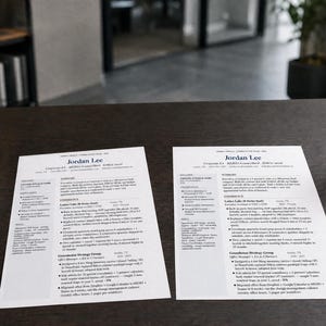 May include: Two resumes with the name "Jordan Lee" are displayed on a dark wooden table. A succulent plant in a concrete pot, a glass of water, and a black pen are also on the table. The resumes are printed on white paper.