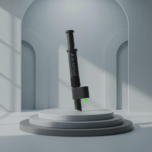 May include: A black cylindrical handheld device featuring the white text BUMPSKE printed vertically on its side. The tool has a plunger-style top, a central grip section, and a lower attachment with a small, bright green accent visible at the base.