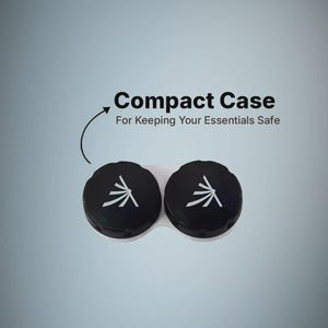 May include: A white contact lens case with two black screw-on caps, each featuring a white stylized graphic. Above the case, the text reads Compact Case For Keeping Your Essentials Safe, with an arrow pointing down toward the lens container.