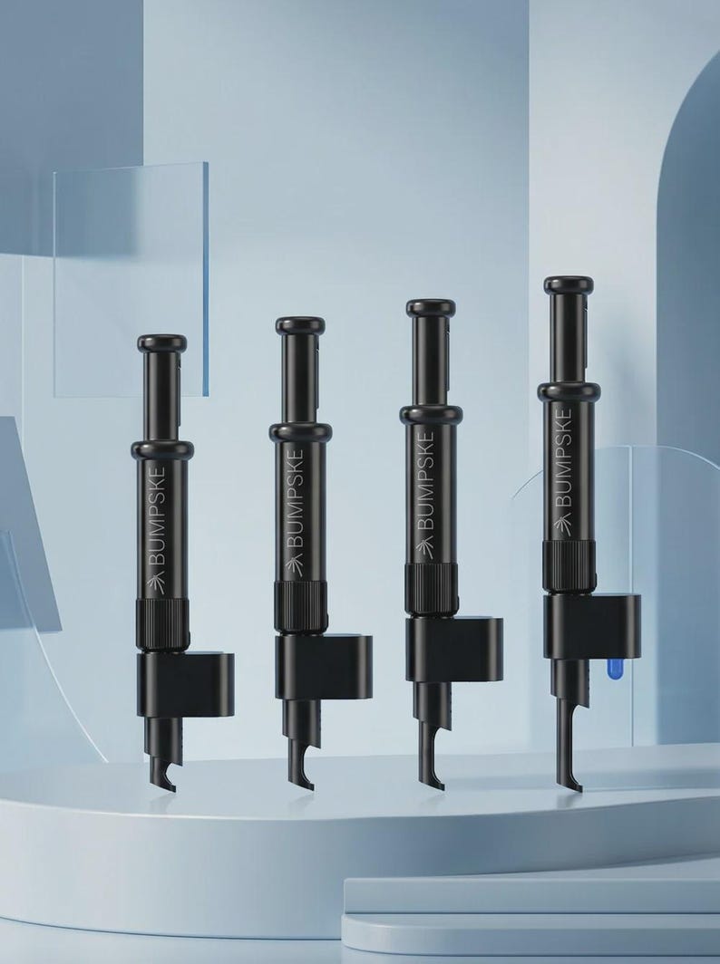 May include: Four black cylindrical tools arranged in a row, each featuring a plunger mechanism at the top and a specialized hook-shaped nozzle at the base. The word BUMPSKE is printed in white text on the side of each black tool body.