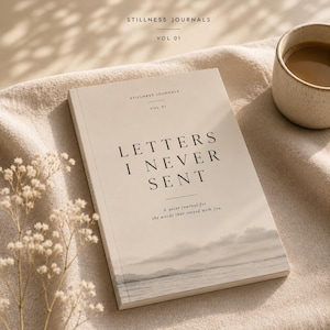 Op de afbeelding: Een beige notitieboek met de titel "LETTERS I NEVER SENT" met de tekst "A quiet journal for the words that stayed with you." Het notitieboek ligt open op een beige oppervlak, naast een kopje koffie en takjes witte bloemen. Het notitieboek maakt deel uit van de "STILLNESS JOURNALS" Vol 01.