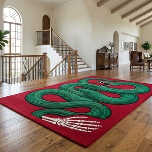 May include: A rectangular area rug featuring a vibrant red background with a large, winding green snake graphic. The snake's body curves across the centre, and a white skeletal hand is positioned at the bottom of the design. The rug has a clean edge.