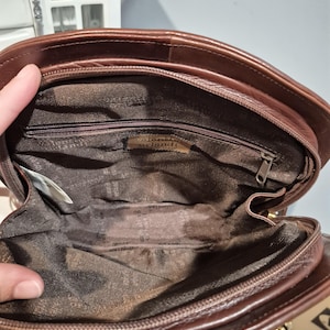 Pu&ograve; includere: Una borsa a mano in pelle marrone con chiusura a zip. L'interno &egrave; foderato con un tessuto fantasia. La borsa ha una forma arrotondata e una chiusura color oro. Il marchio "Valentino Orlandi" &egrave; visibile all'interno della borsa.