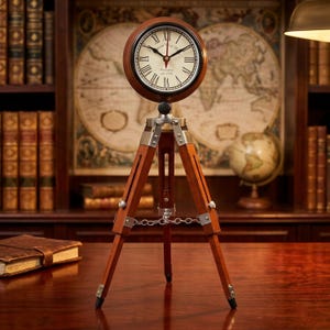 May include: A round analog clock with a white face, black Roman numerals, and a red second hand, mounted on a brown wooden tripod stand with silver metal hardware and a small silver chain connecting the three legs for stability and support.