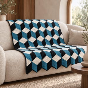 May include: A crochet blanket featuring a geometric pattern of repeating cubes in shades of black, white, and teal blue. The textile displays a three-dimensional optical illusion effect created by the arrangement of colored diamond-shaped stitches.