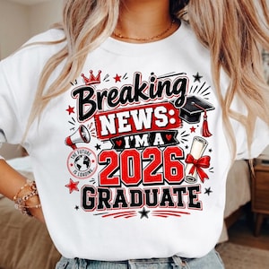 May include: White sweatshirt with a graphic that reads "Breaking News: I'm a 2026 Graduate." The design includes a graduation cap, diploma, and stars in red, black, and white. The phrase "The Future is Loading" is also included.
