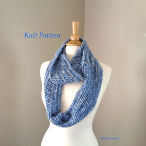 May include: Knit Pattern - A blue and white infinity scarf on a white mannequin. The scarf is made with a simple knit stitch and has a textured look.
