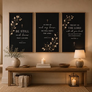 May include: Three framed black wall art prints with gold botanical accents and religious quotes. The prints are displayed above a wooden bench with a woven basket, a candle, and decorative items. The room has a warm, inviting atmosphere.