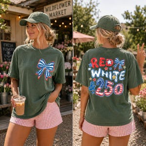 May include: An olive green t-shirt featuring a small red, white, and blue bow graphic on the front left chest. The back displays the text RED WHITE & 250 in a stylized font with stars and bow accents. The shirt is paired with pink gingham shorts.