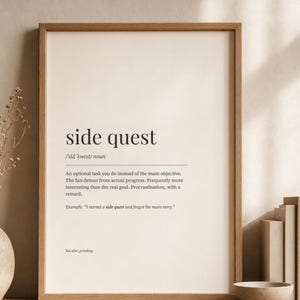 May include: A framed wall art print featuring a dictionary-style definition of the term side quest. The text includes the phonetic spelling, noun classification, a descriptive definition, an example sentence, and a see also reference to grinding.
