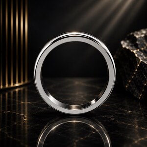 Peut inclure: Une bague en métal argenté poli avec une surface lisse et plate et un anneau circulaire. La bague présente une finition propre et réfléchissante qui capte la lumière, créant un éclat brillant le long du bord supérieur de la circonférence.
