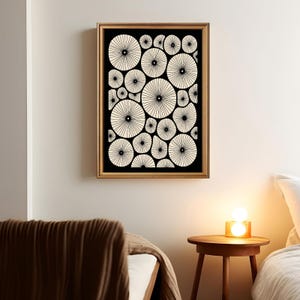 May include: A framed wall art print featuring a black background with numerous off-white circular shapes. Each circle contains a central dot with thin, radiating lines extending to the edges, creating a pattern of repeating, organic, flower-like forms.