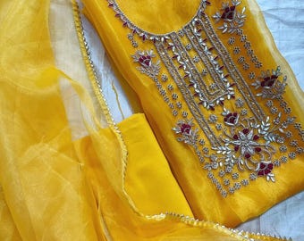 May include: A bright yellow semi-sheer tunic featuring intricate silver embroidery around the neckline and chest, accented with small deep red floral motifs. The garment includes a matching yellow sheer dupatta with a delicate silver border trim.