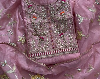 May include: A light pink fabric garment featuring intricate silver metallic embroidery, sequins, and small floral accents in shades of magenta and orange. The design includes a central vertical panel with detailed leaf patterns and a scalloped border.