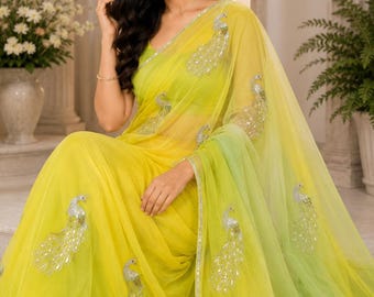May include: A vibrant yellow saree with a gradient to lime green, adorned with silver peacock embroidery. The sheer fabric drapes elegantly. The saree is a traditional garment, perfect for special occasions.