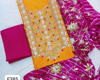 May include: A bright yellow tunic featuring intricate gold embroidery and mirror work on the front, paired with a solid magenta fabric piece and a magenta dupatta with white horizontal stripes and gold floral embellishments, labeled with F385.