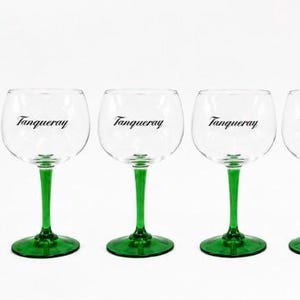 Może przedstawiać: Zestaw sześciu przezroczystych kieliszk&oacute;w do ginu z zielonymi n&oacute;żkami i podstawami. Na każdym kieliszku znajduje się czarny napis "Tanqueray". Kieliszki mają około 18 cm wysokości.