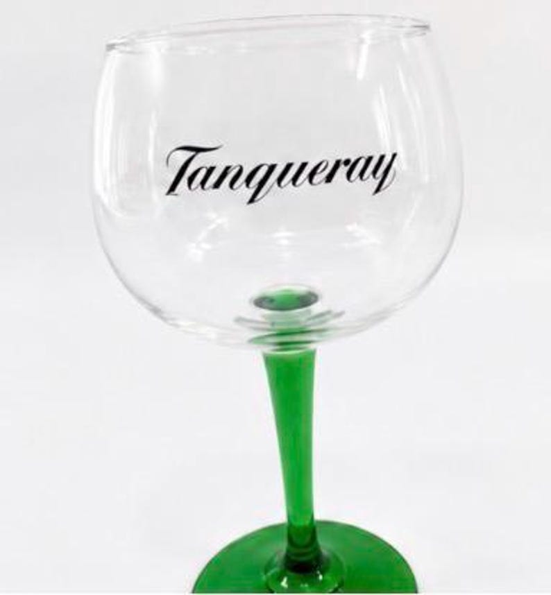 Może przedstawiać: Przezroczysty kieliszek do ginu z zieloną n&oacute;żką i podstawą. Na szkle czarnym skryptem wydrukowano słowa "Tanqueray". Kieliszek przeznaczony jest do koktajli i innych napoj&oacute;w.