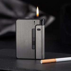 May include: A silver-coloured lighter with a flame, next to a cigarette. The lighter has a rectangular shape with a brushed metal finish. The flame is yellow and orange. The cigarette is white with a brown filter.