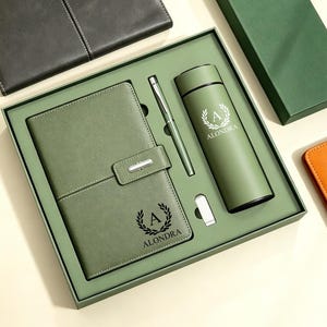 Peut inclure: Un coffret cadeau vert sauge contenant un carnet à fermeture magnétique, un stylo argenté, une petite clé USB argentée et une bouteille isotherme cylindrique. Chaque article porte un logo couronne de laurier avec la lettre A et le nom ALONDRA.