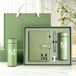 Op de afbeelding: Een saliegroene cadeauset met een notitieboek met riemsluiting, een cilindrische thermosfles en een pen. Het notitieboek en de thermosfles zijn gepersonaliseerd met de letter M en de naam Matthew. De set bevat een bijpassende groene geschenktas.