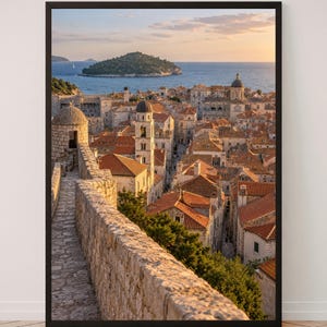 Peut inclure: Une impression d'art encadrée montrant une vue en plongée d'une ville côtière avec des remparts en pierre, des toits en terre cuite et un clocher. La scène comprend une mer bleue calme et une île lointaine sous un ciel de coucher de soleil.