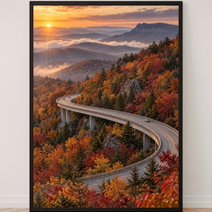 Könnte beinhalten: Ein gerahmter Kunstdruck mit einer Landschaftsaufnahme aus der Vogelperspektive, die eine geschwungene Betonbrücke zeigt, welche sich durch einen dichten Herbstwald mit leuchtend roten, orangen und gelben Blättern unter einem goldenen Sonnenaufgangshimmel schlängelt.