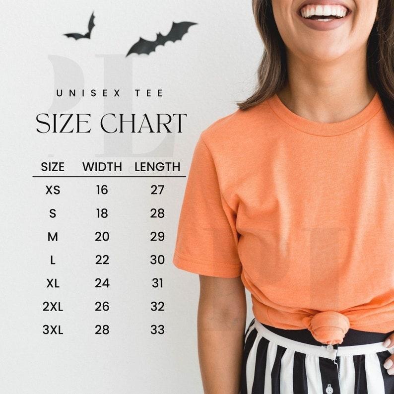 May include: Orange unisex tee shirt with a size chart. The size chart shows the width and length measurements for sizes XS to 3XL. The shirt is knotted at the waist. Two black bat silhouettes are at the top.