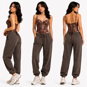 May include: A brown floral print corset top with spaghetti straps and a lace-up back. Paired with dark brown sweatpants with a drawstring waist and elastic cuffs. The model is wearing white sneakers.