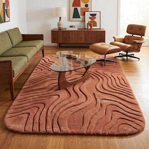 May include: A rectangular area rug in a solid terracotta color featuring a raised, carved texture with flowing, organic wavy lines that create a topographic pattern across the entire surface of the soft, plush floor covering.