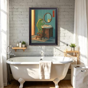 May include: A framed wall art print featuring a green frog standing on a wooden stool in a bathroom, looking into a round mirror above a sink. The illustration uses a teal tiled background and includes vertical Japanese text on the right side.