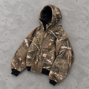 Pode incluir: Um casaco com capuz com padrão de camuflagem em tons de castanho, bege e branco. O casaco tem um fecho de correr frontal, punhos e bainha canelados em preto e um forro interior preto. Um pequeno logótipo da marca Carhartt está na parte frontal.