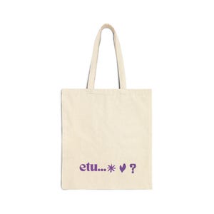 Peut inclure: Sac fourre-tout crème avec texte violet "etu...* ♥ ?". Le sac a deux anses et est fait d'un tissu robuste. Le design est simple et moderne, adapté pour transporter des livres, des courses ou des effets personnels.