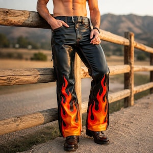 Könnte beinhalten: Schwarze Lederhose mit einem leuchtend orangefarbenen und roten Flammengrafikmuster an den Unterschenkeln. Die Hose verfügt über einen schwarzen Ledergürtel mit silberfarbener Metallschnalle, sichtbare rote Nähte und ein klassisches Fünf-Taschen-Design.