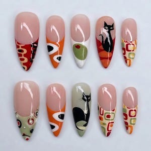 May include: A set of ten almond-shaped press-on nails featuring a nude base with various designs on the tips. Patterns include black cat silhouettes, green olives, and geometric shapes in red, orange, cream, and olive green with a glossy finish.