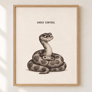 Pode incluir: Uma impressão de arte emoldurada com uma ilustração a carvão de uma cobra enrolada segurando um pequeno comando de videojogos. A cobra tem uma expressão concentrada e o texto "UNDER CONTROL" está impresso a preto acima da cabeça.
