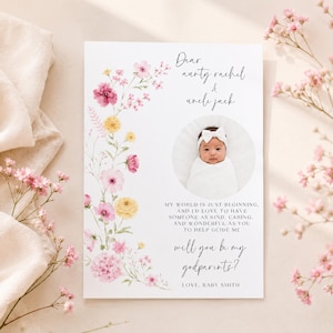 Op de afbeelding: Een witte rechthoekige kaart met een bloemenrand van roze en gele bloemen aan de linkerkant. De tekst luidt Dear aunty rachel & uncle jack, gevolgd door een ronde foto van een baby en de vraag Will you be my godparents?