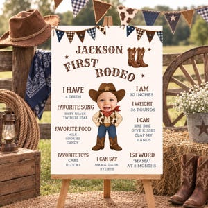 May include: A white milestone birthday sign titled Jackson First Rodeo featuring brown cowboy boots, a bunting banner, and a cartoon illustration of a baby in western attire with text detailing age, height of 30 inches, weight of 36 pounds, and milestones.