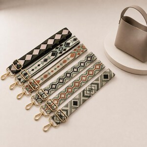 Puede incluir: Seis correas ajustables para bolsos con diversos patrones geométricos tejidos en tonos verde oliva, beige, marrón y negro. Cada correa está equipada con mosquetones giratorios de metal dorado y hebillas rectangulares para ajustar.