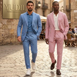May include: Two men walking on a cobblestone street, wearing tailored suits. One suit is light blue, paired with a blue polo shirt and white sneakers. The other is a pink double-breasted suit with a white shirt and brown shoes. A gold sign reads "YUDIL PREMIUM TAILORING SINCE 2012."