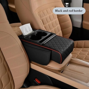 May include: Black car console organizer with a red border, featuring a diamond-quilted pattern. Includes cup holders, a tissue dispenser, and a small storage pocket. The text "Black and red border" is visible.