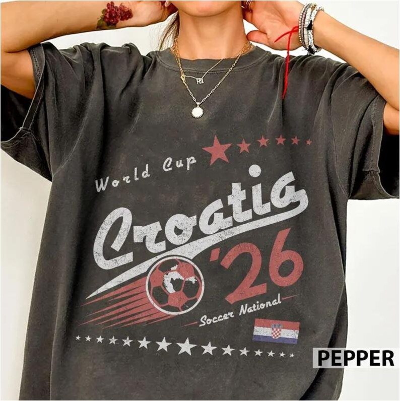 May include: A charcoal gray short-sleeve t-shirt featuring a distressed graphic with the text World Cup Croatia '26 Soccer National. The design includes a soccer ball, a row of stars, and the Croatian flag in red, white, and blue colors.
